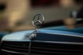 Old rare vintage green Mercedes-Benz hood, badge, radiator grille on blurred background. The symbol of rich life.