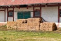 Old rectangular hay bales stored in front of abandoned farm building Royalty Free Stock Photo