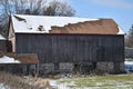 Old red barn in early winter with just a touch of snow on a sunny day on a farm Royalty Free Stock Photo