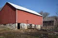 Old red barn in early winter with just a touch of snow on a sunny day on a farm Royalty Free Stock Photo