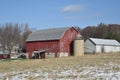 Old red barn in early winter with just a touch of snow on a sunny day on a farm Royalty Free Stock Photo