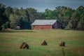 Old red barn and rotobales on farm landscape in the south Royalty Free Stock Photo