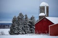 Old red barn and silos next to a  Wisconsin, snow covered forest Royalty Free Stock Photo