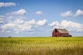 Old red barn sitting in a field in the distance under a blue sky with white clouds.