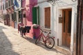 Old red bicycle parked long an external wall in Burano island, V Royalty Free Stock Photo