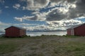 Old red boathouses in summer with snowy mountain and blue fjord background Royalty Free Stock Photo