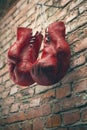 Old red boxing gloves hang on nail on brick wall with copy space for text. High resolution 3d render Royalty Free Stock Photo