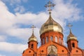 Old red brick Christian church with gold and gilded domes against a blue sky. Concept faith in god, orthodoxy, prayer Royalty Free Stock Photo