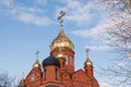 Old red brick Christian church with golden and gilded domes against a blue sky and tree branches. Concept faith in god, orthodoxy Royalty Free Stock Photo