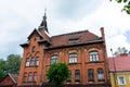 An old red brick house. Part of the red brick wall, windows and a fragment of the roof of an old residential building against the