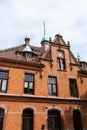 Part of the red brick wall, windows and a fragment of the roof of an old residential building against the sky. Royalty Free Stock Photo