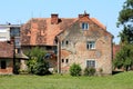 Old red brick suburban family house with cracked facade and windows with dilapidated wooden frames surrounded with grass and trees Royalty Free Stock Photo