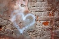 Old red brick wall with cracks and scratches and painted heart. Distressed wall with broken bricks texture Royalty Free Stock Photo