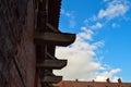 Old red brick wall and tiled roof of a medieval castle against the blue sky with white clouds. The background Royalty Free Stock Photo
