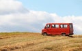 Old red bus standing in the middle of the field