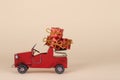 Old red car carrying Christmas or New Year  gifts isolated on a beige background Royalty Free Stock Photo