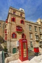 An old red cardphone booth in the historic city Valletta with an old appartment building in the background Royalty Free Stock Photo