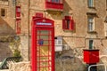 An old red cardphone booth in the historic city Valletta with an old appartment building in the background Royalty Free Stock Photo