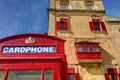 An old red cardphone booth in the historic city Valletta with an old appartment building in the background Royalty Free Stock Photo