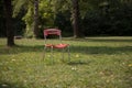 Old red chair in park on a green grass. Complementary colours. Royalty Free Stock Photo