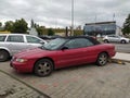 Old red Chrysler Stratus convertible car parked