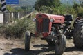 An old red classic tractor left on the soil road side near a bridge with a sign written Greenriver. Royalty Free Stock Photo