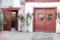 Old red doors with wrought iron details and colorful rose plant Royalty Free Stock Photo