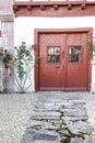 Old red doors with wrought iron details and colorful rose plant Royalty Free Stock Photo