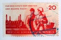 An old red east german postage stamp with postal soldiers guarding a factory and a worker