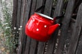 Old red enamel kettle with white polka dots on a wooden fence. Retro things for decor. Garden background Royalty Free Stock Photo