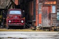 Old Red Truck by Abandoned Building