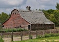 An old red hip roofed barn in serious deterioration