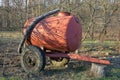 Old red iron barrel on wheels stands outdoors