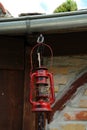 Old red lantern hanging by wood under canopy roof on a brick wall