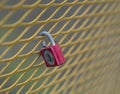 Old red lock hanging locked on the yellow metal grating Royalty Free Stock Photo