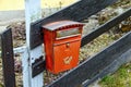 Old red mailbox on a wooden fence. Austria.