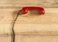 Red old fashioned telephone receiver on wooden table Royalty Free Stock Photo