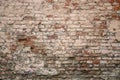 Old red shabby damaged brick wall with gray cement, stains of white paint. rough surface texture Royalty Free Stock Photo