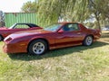 Old red sport Chevrolet Camaro coupe 1982 - 1992 by GM parked on the grass. Classic muscle car.