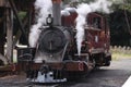 Old red steam train with steam being released from the engine