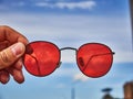 Old red sunglasses in hand. Scratched glass