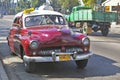 Old red taxi driving through the streets of Havana Cuba