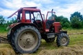 Old red tractor in the field during the haymaking season, pressing hay on bales, forage harvesting Royalty Free Stock Photo