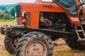 Old red tractor in the field during the haymaking season, pressing hay on bales, forage harvesting Royalty Free Stock Photo