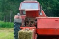 Old red tractor in the field during the haymaking season, pressing hay on bales, forage harvesting Royalty Free Stock Photo