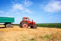 old red tractor and trailers during wheat harvest on cloudy summer day Royalty Free Stock Photo