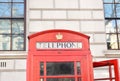 Old red traditional English phone booth top in sunlit London.