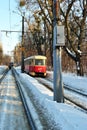 Old red tram passed snowy park, back view, railroad along trees line, winter sunny day