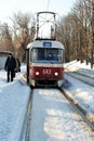 Old red tram stops in snowy park, winter sunny day