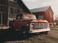 An old red truck parked in front of a barn. Generative AI image. Royalty Free Stock Photo